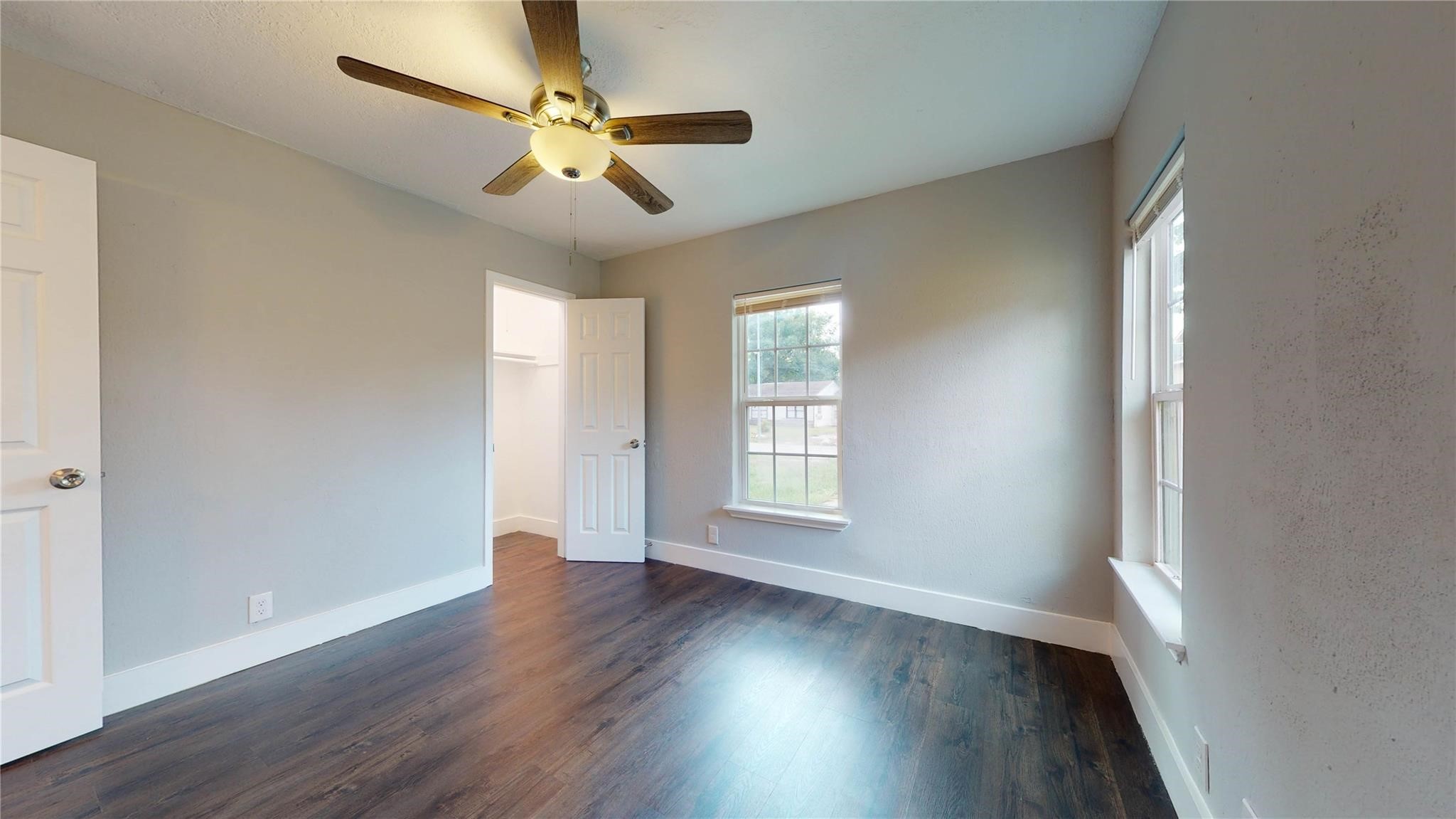 7346 Iwo Jima Road Houston, TX 77033 - Photo 11 of 20 Bright room with hardwood floors, a ceiling fan, and two windows for natural light. Includes a walk-in closet, ideal for storage.