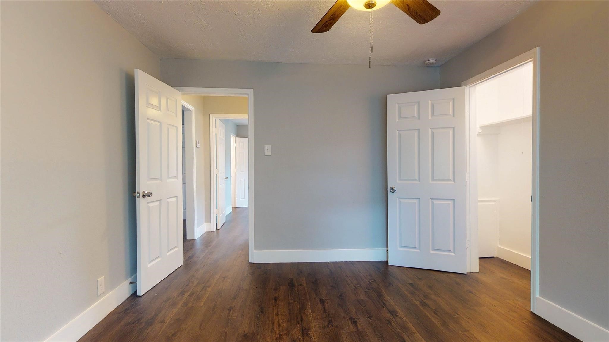 7346 Iwo Jima Road Houston, TX 77033 - Photo 14 of 20 This room features hardwood floors, a ceiling fan, and neutral walls. It has two doors: one leading to a hallway and the other to a walk-in closet, offering practical storage and easy access.