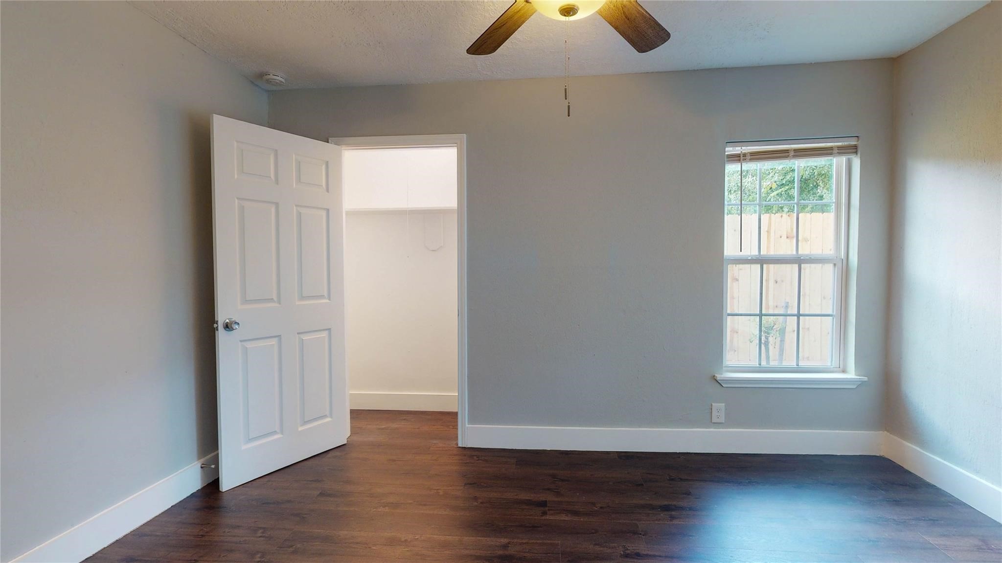 7346 Iwo Jima Road Houston, TX 77033 - Photo 16 of 20 This room features warm wood flooring, a ceiling fan, and natural light from a window. It has neutral walls and a white door leading to a closet, creating a bright and inviting space.