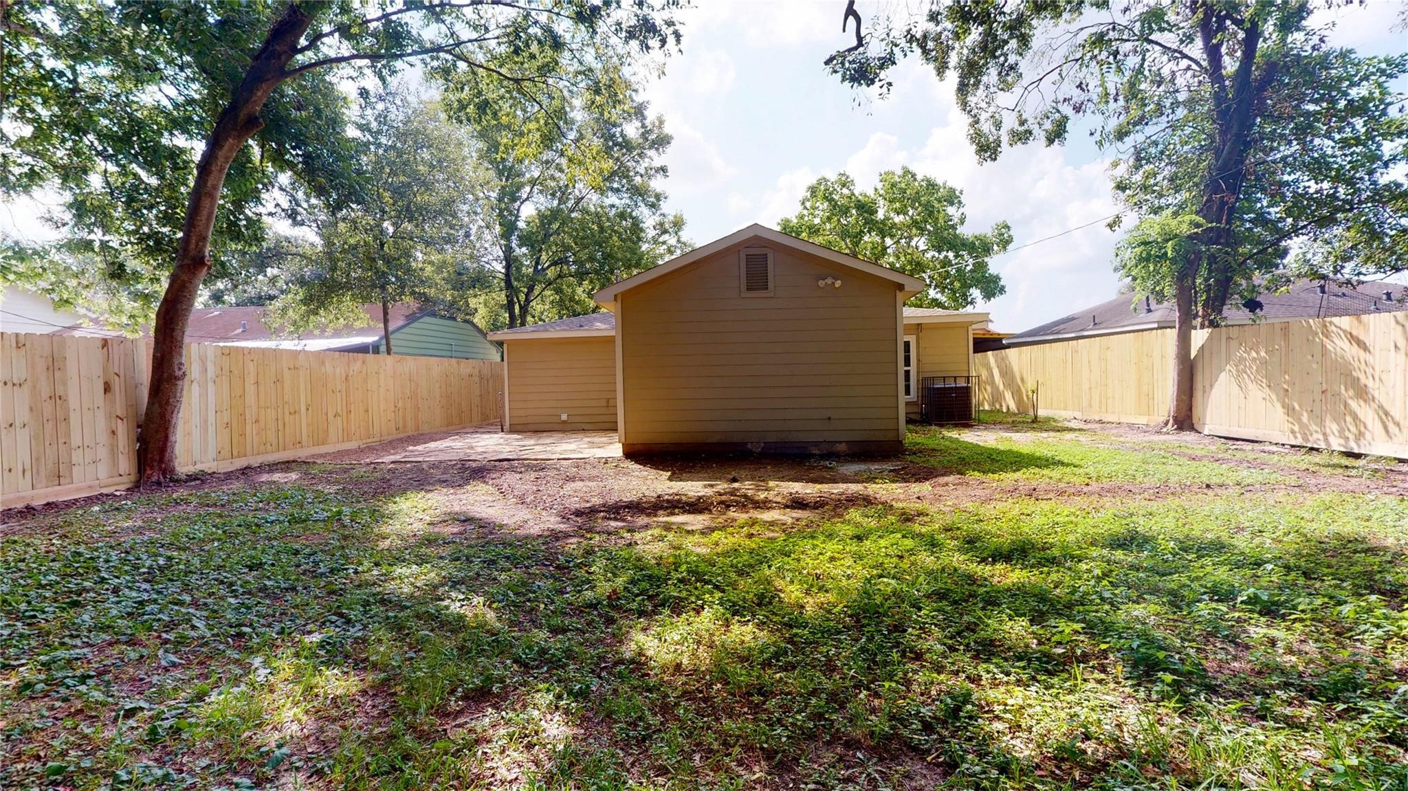 7346 Iwo Jima Road Houston, TX 77033 - Photo 20 of 20 This photo shows a spacious backyard with a small house and a wooden fence surrounding the area. There are mature trees providing shade, making it an ideal space for outdoor activities and relaxation.