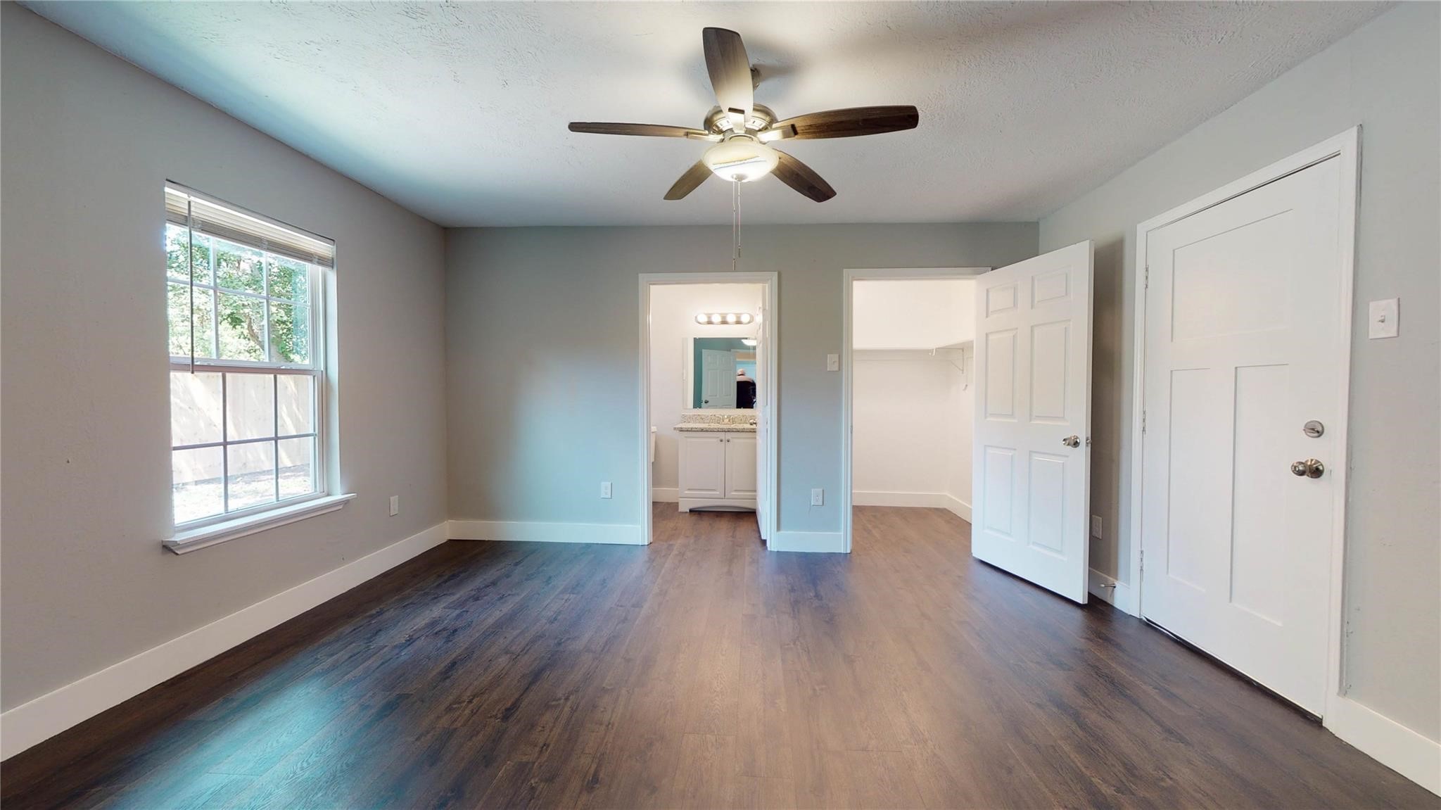 7346 Iwo Jima Road Houston, TX 77033 - Photo 6 of 20 This room features modern wood flooring, neutral walls, and a ceiling fan. It has ample natural light from a large window, and direct access to a bathroom and walk-in closet, making it ideal for a bedroom.