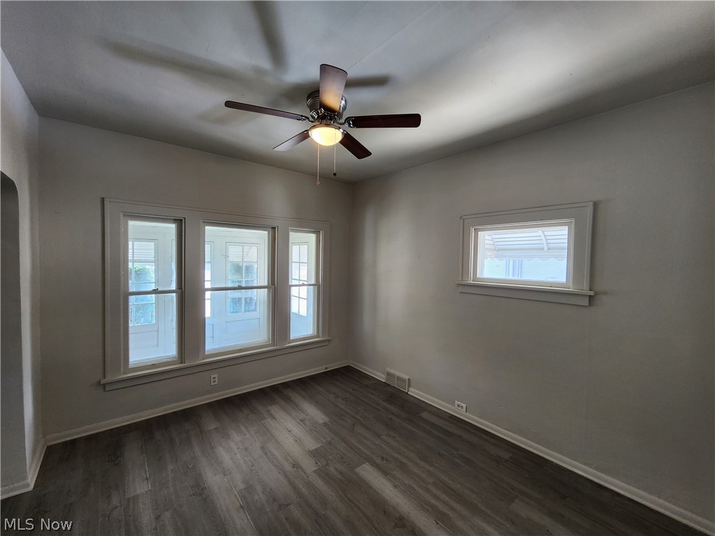 7202 Snow Road Parma, OH 44129 - Photo 8 of 14 Unfurnished room with dark hardwood / wood-style flooring, ceiling fan, and a healthy amount of sunlight