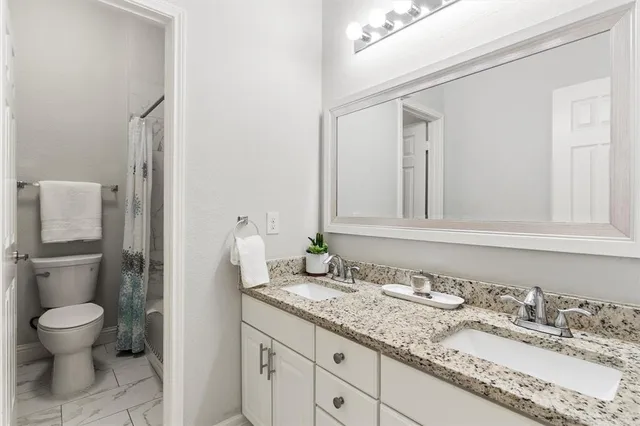 a bathroom with a granite countertop sink and a toilet