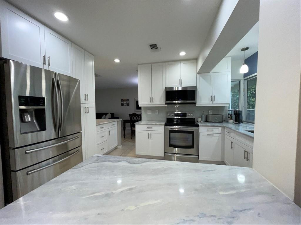 2358 Northwest 31st Street Boca Raton, FL 33431 - Photo 3 of 11 a kitchen with granite countertop a refrigerator stove and microwave