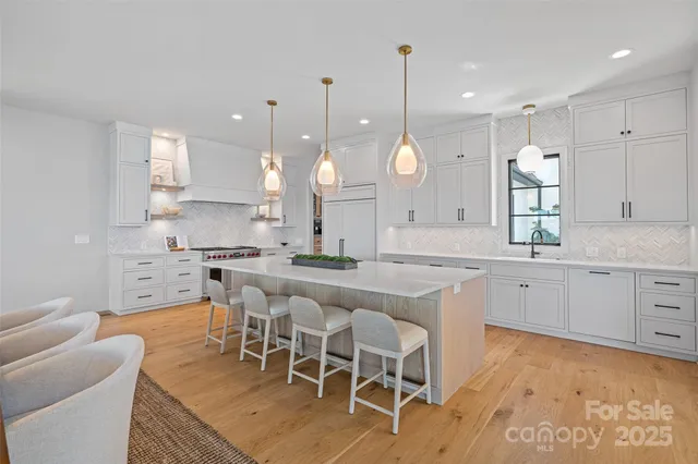 a large kitchen with kitchen island a island a sink a stove a dining table and chairs