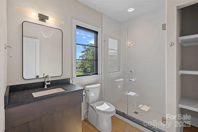 a bathroom with a sink a toilet a mirror and shower