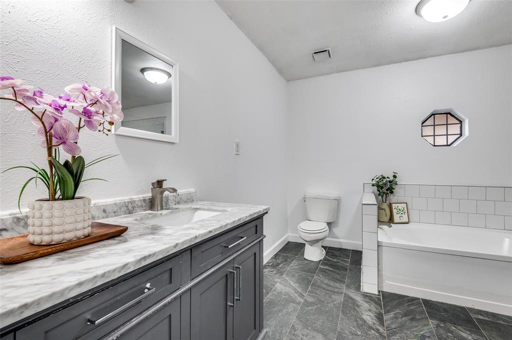 1805 Etain Road Irving, TX 75060 - Photo 12 of 23 a bathroom with a granite countertop sink a toilet and a mirror