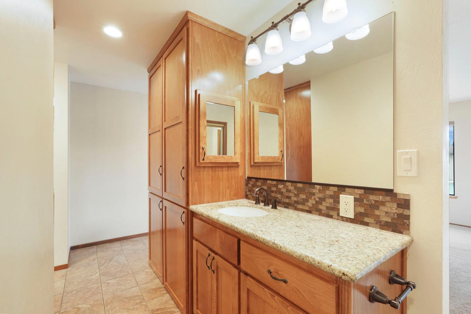 22022 South 99 Frontage Road Ripon, CA 95366 - Photo 21 of 46 a bathroom with a granite countertop sink and a mirror