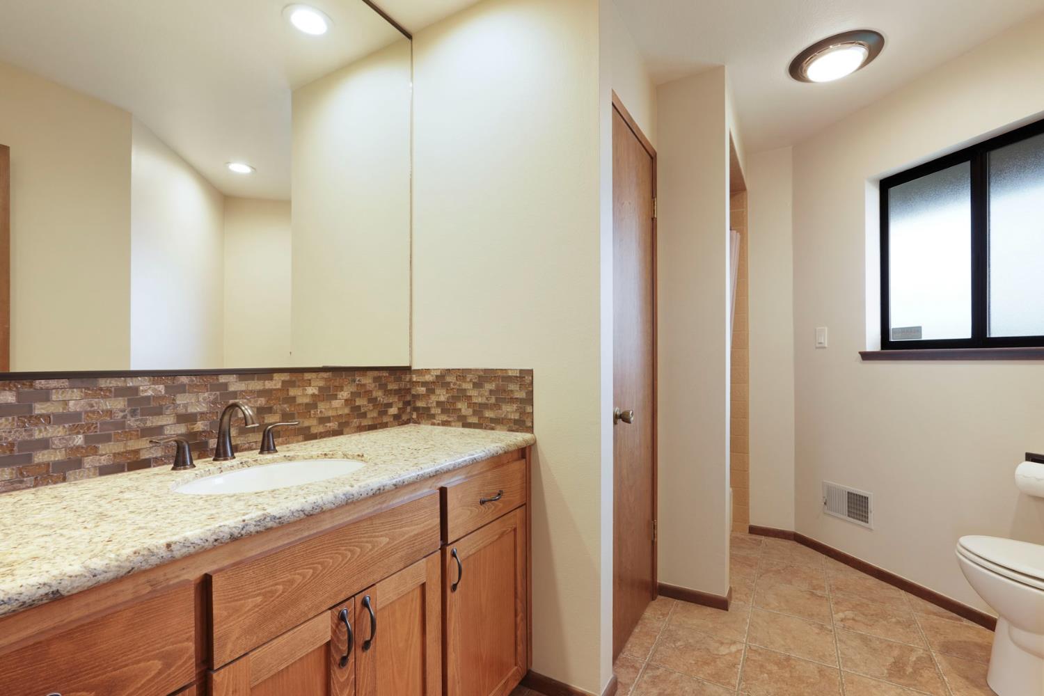 22022 South 99 Frontage Road Ripon, CA 95366 - Photo 25 of 46 a bathroom with a granite countertop sink and a mirror