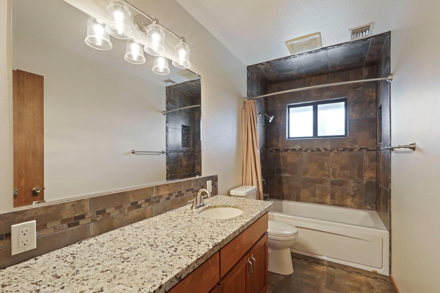 22022 South 99 Frontage Road Ripon, CA 95366 - Photo 29 of 46 a bathroom with a granite countertop sink a toilet and bathtub