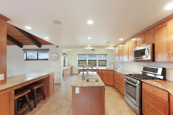 a large kitchen with stainless steel appliances granite countertop a stove and a sink