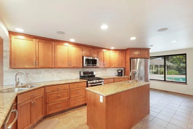 a kitchen with stainless steel appliances granite countertop a sink counter space cabinets and a large window
