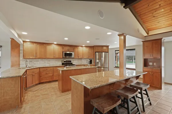 a large kitchen with granite countertop lots of counter space dining table and stainless steel appliances