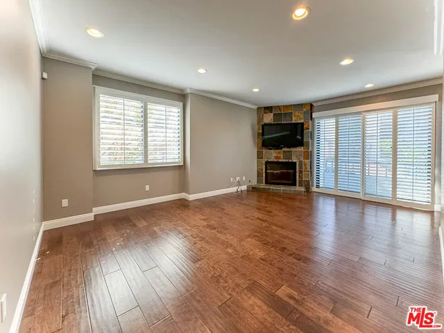 an empty room with wooden floor fireplace and windows