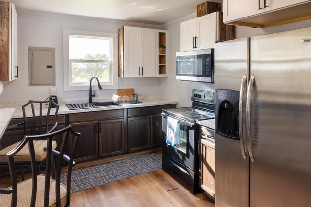 a kitchen with stainless steel appliances granite countertop a refrigerator a stove a sink a dining table and chairs