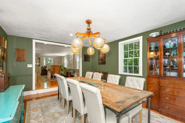 a dining room with wooden floor a chandelier a wooden table and chairs