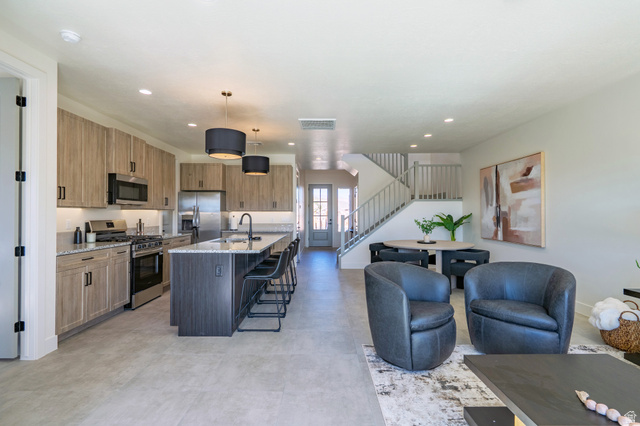 2972 West 570 North Hurricane, UT 84737 - Photo 32 of 104 Kitchen with light stone counters, stainless steel appliances, a kitchen island with sink, a kitchen breakfast bar, and hanging light fixtures