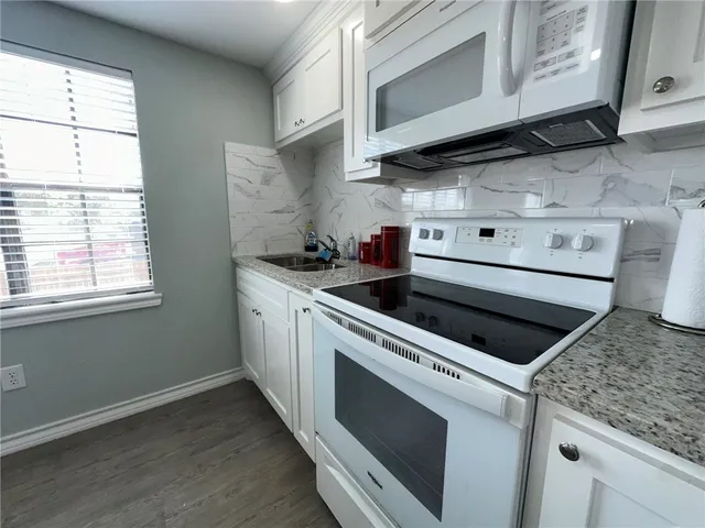 a kitchen with stainless steel appliances white cabinets and a stove top oven