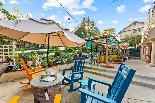 a view of a patio with a dining table and chairs under an umbrella with a fire pit