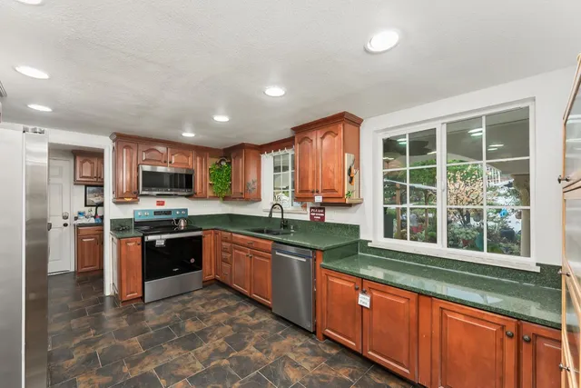 a large kitchen with stainless steel appliances granite countertop a granite counter tops and a large window