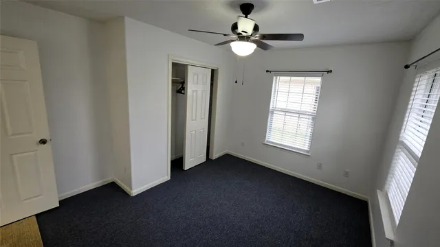 an empty room with windows and fan