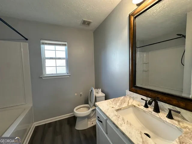 a bathroom with a granite countertop sink toilet and mirror