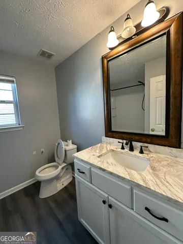 a bathroom with a granite countertop sink a mirror and toilet