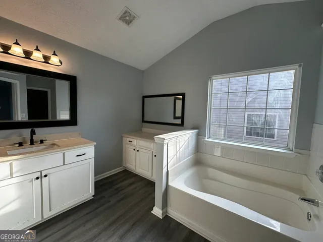 a bathroom with a tub a sink and a large mirror