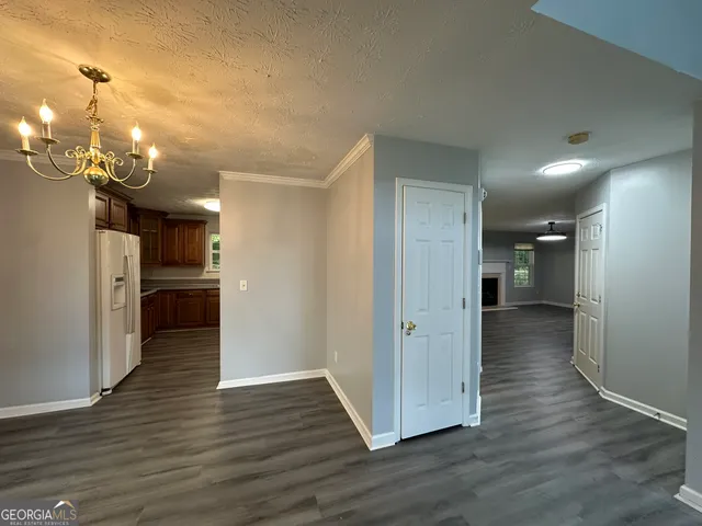 a view of a hallway with wooden floor and a kitchen