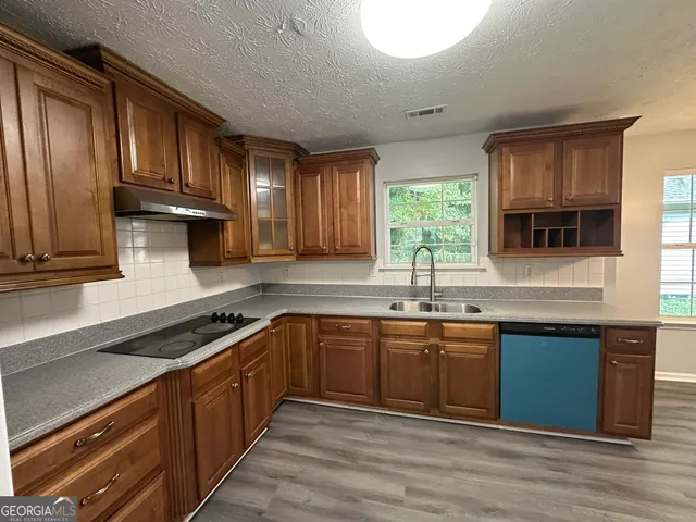 a kitchen with stainless steel appliances granite countertop wooden cabinets a sink and a stove