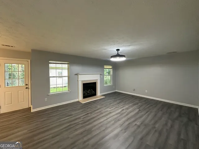 an empty room with wooden floor fireplace and windows