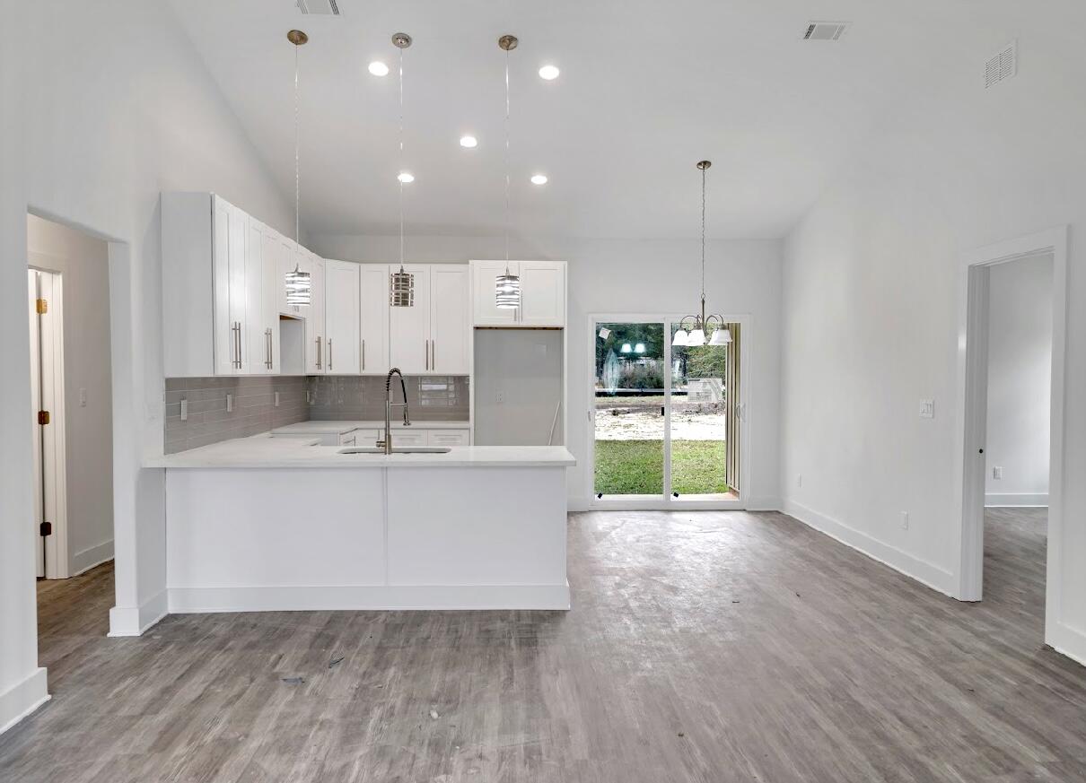 117 Buckeye Street DeFuniak Springs, FL 32433 - Photo 8 of 26 a large white kitchen with kitchen island a sink wooden floor and a refrigerator