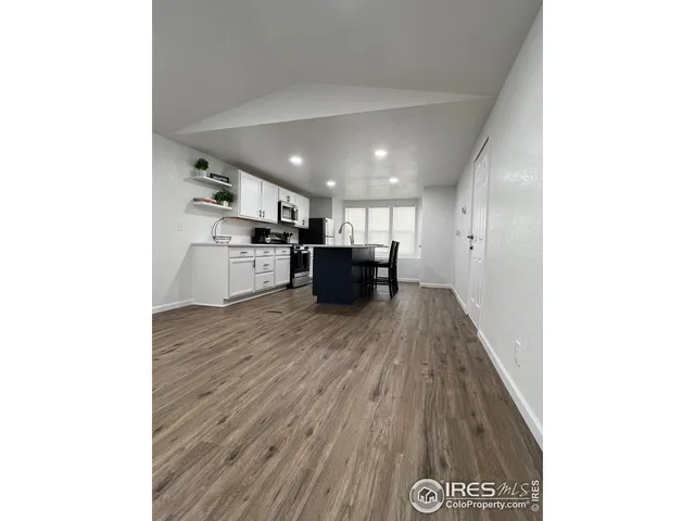 a kitchen with a wooden floor and a living room