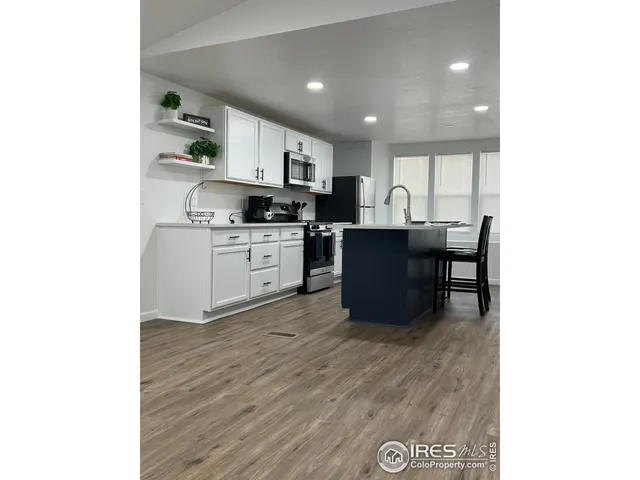 a kitchen with stainless steel appliances granite countertop a sink cabinets and wooden floor