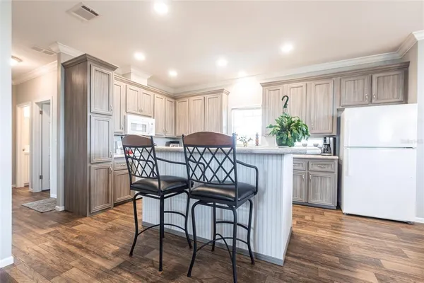 a kitchen with stainless steel appliances granite countertop a dining table chairs refrigerator and a window