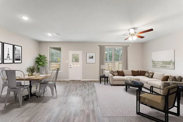 a living room with furniture two window and wooden floor