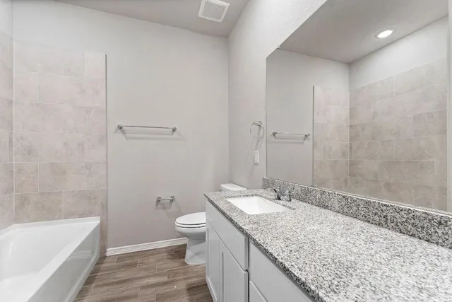 a bathroom with a granite countertop sink a toilet and bathtub