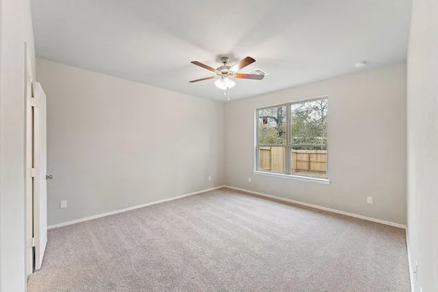 an empty room with a window and a fan