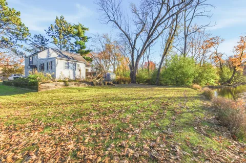 a view of a house with a big yard and large trees