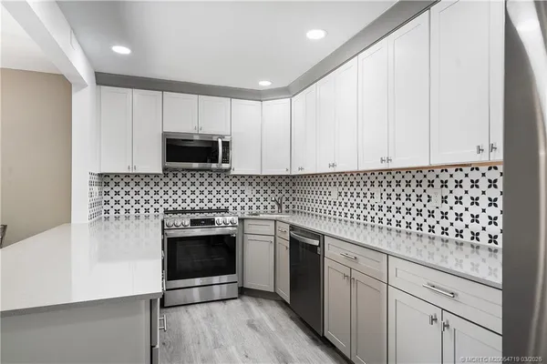 a kitchen with granite countertop white cabinets and stainless steel appliances