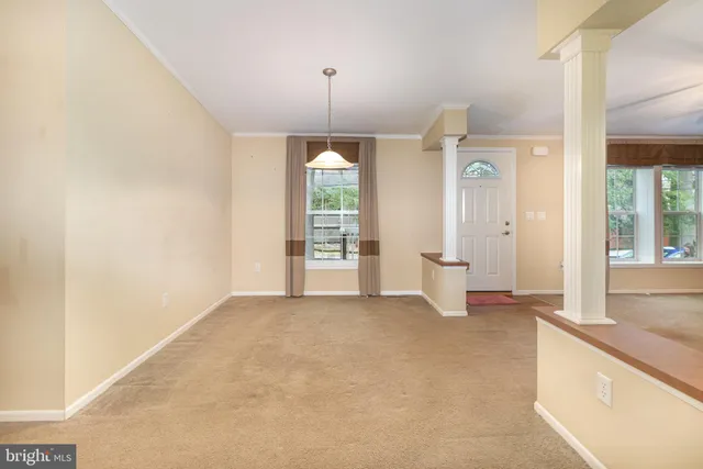 an empty room with chandelier fan and windows