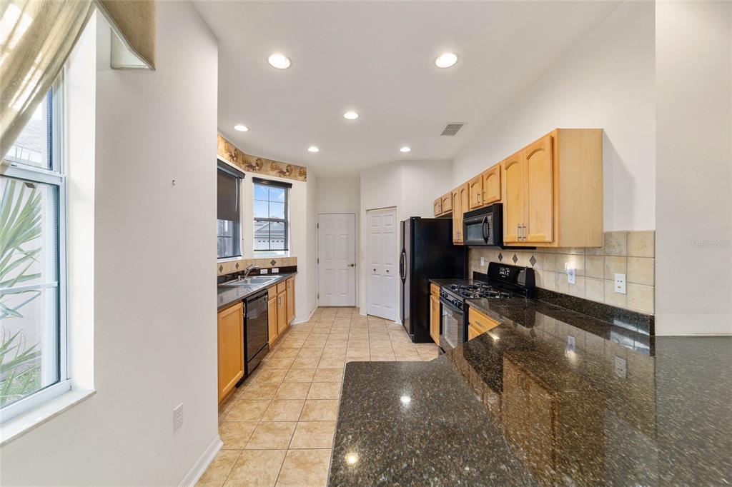 8434 Southwest 82nd Loop Ocala, FL 34481 - Photo 17 of 41 a kitchen with stainless steel appliances kitchen island granite countertop a stove a sink and a microwave