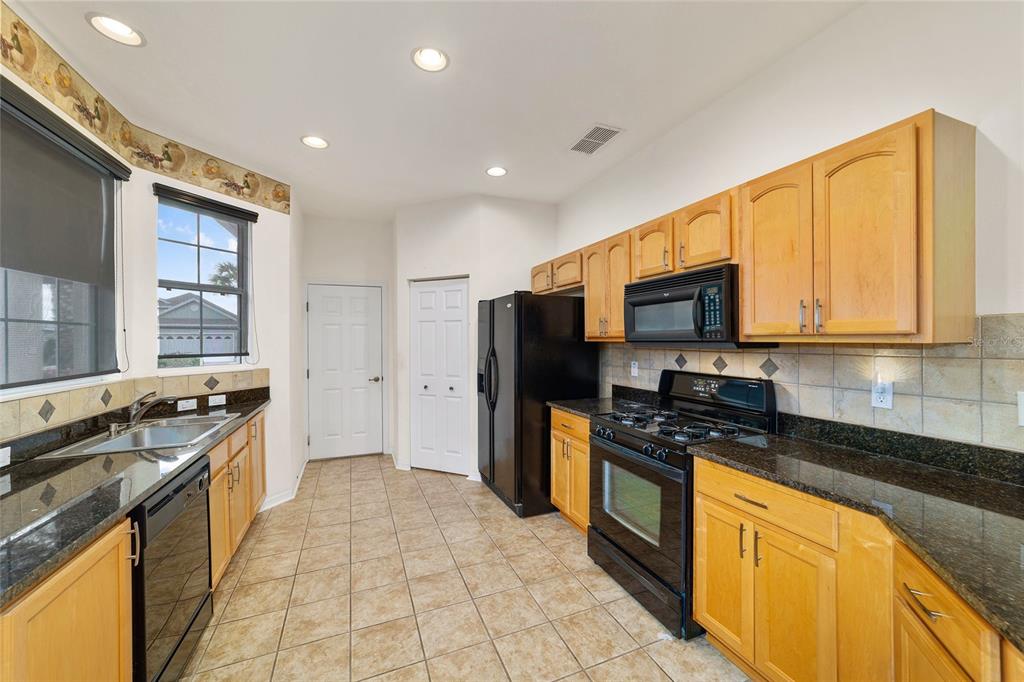 8434 Southwest 82nd Loop Ocala, FL 34481 - Photo 18 of 41 a kitchen with stainless steel appliances granite countertop a stove top oven a sink dishwasher a refrigerator and cabinets with wooden floor