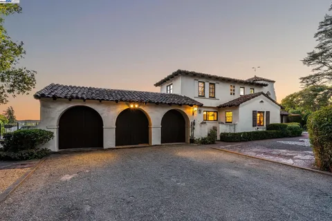 a front view of a house with large trees