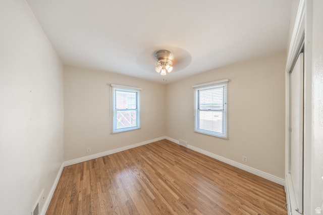 193 Locust Street Clearfield, UT 84015 - Photo 13 of 29 Spacious room featuring wood-finish flooring, light neutral wall tones, two windows with blinds, white trim, and a ceiling-mounted light fixture