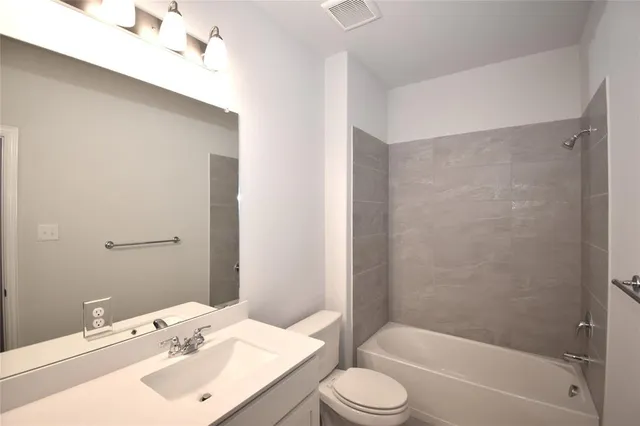 a bathroom with a bathtub shower sink vanity and toilet