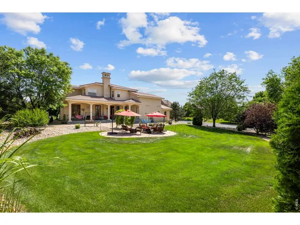 a backyard of a house with large trees and plants