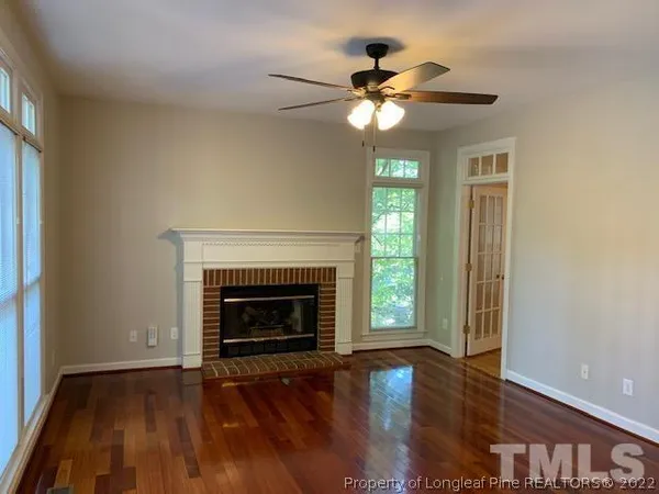 a view of an empty room with wooden floor fireplace and a window