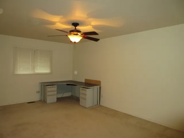 a view of a room with a hanging chair and a ceiling fan