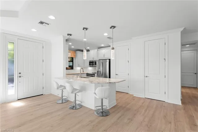 a large kitchen with lots of counter space a sink appliances and living room view